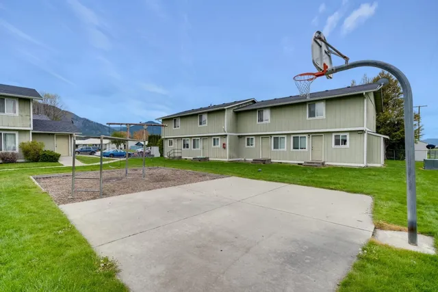 a view of a house with a big yard plants and large tree