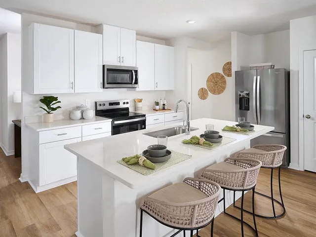 a kitchen with stainless steel appliances granite countertop a dining table chairs and a refrigerator