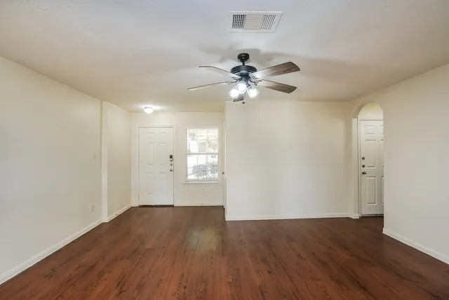 a view of an empty room with a window and wooden floor