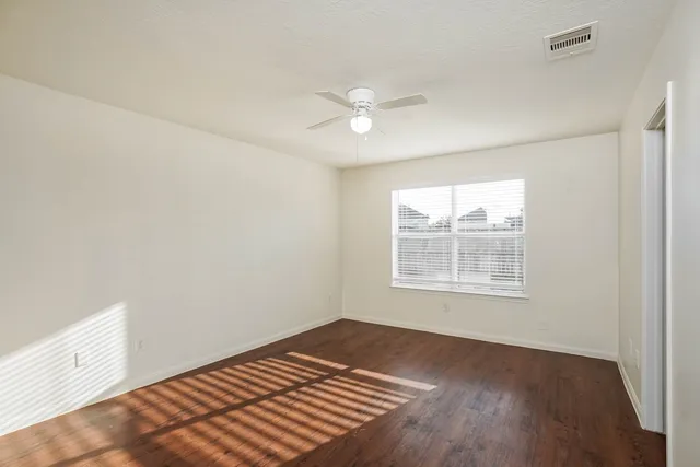 a view of an empty room with a window and wooden floor