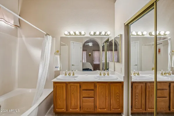 a bathroom with a double vanity sink mirror and bathtub