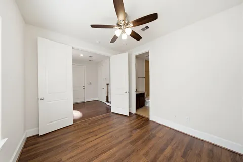 an empty room with wooden floor and a ceiling fan