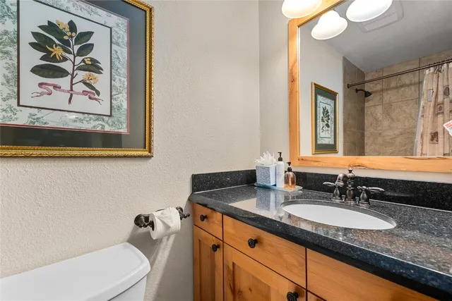 a bathroom with a granite countertop sink mirror and toilet