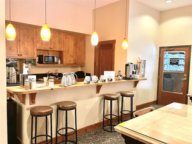a kitchen with kitchen island granite countertop a table chairs sink and cabinets
