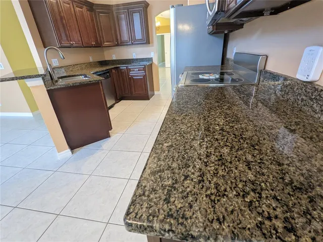 a kitchen with granite countertop a stove a sink and a refrigerator