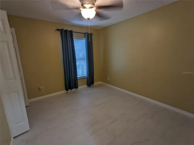 an empty room with a chandelier fan and a window