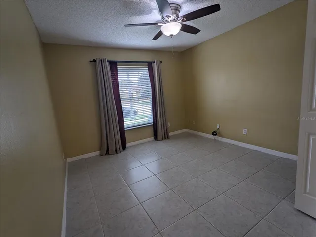 an empty room with windows and fan