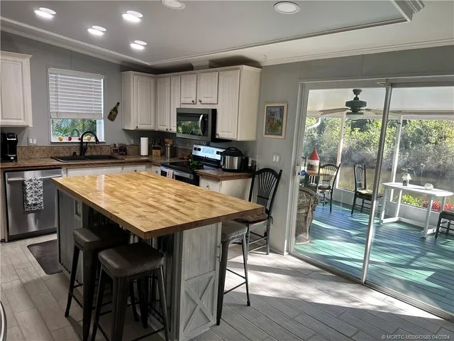 a kitchen with stainless steel appliances kitchen island granite countertop a refrigerator a stove and white cabinets with wooden floor