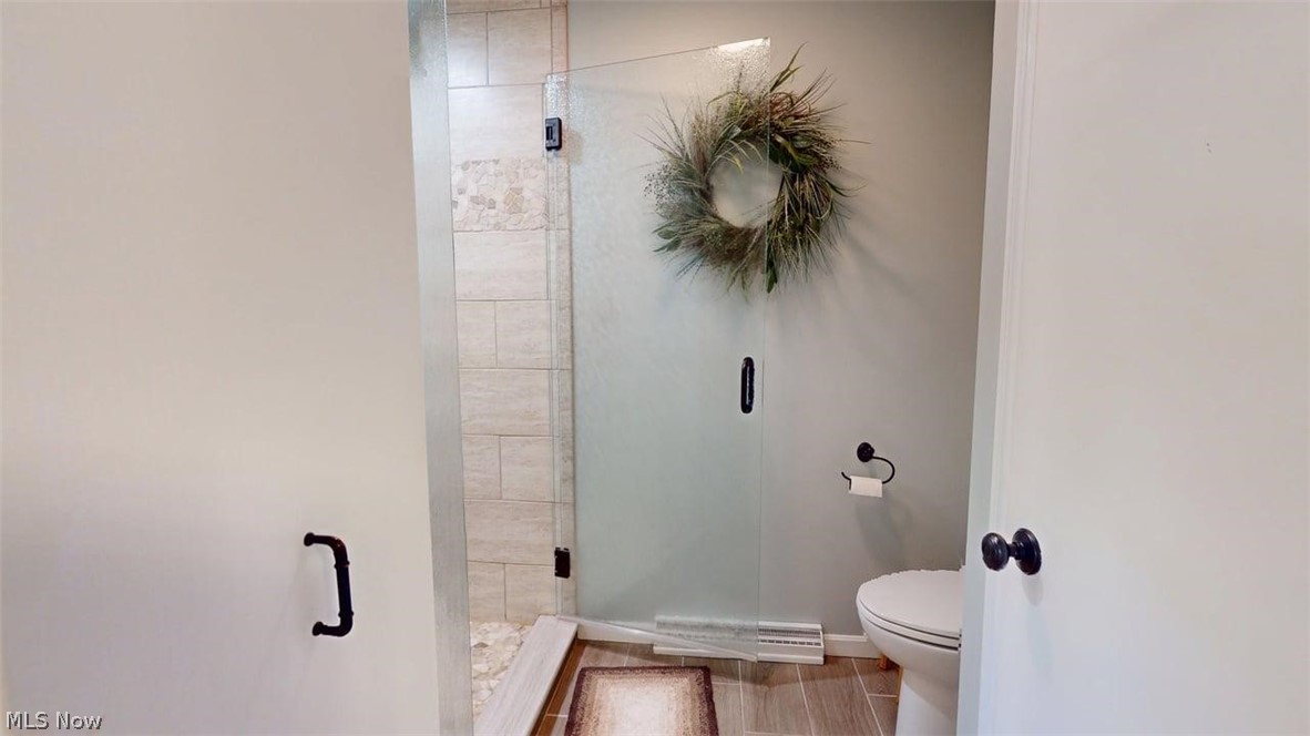 3985 Wiers Road Willard, OH 44890 - Photo 26 of 50 Bathroom featuring a frameless glass shower enclosure, tiled shower surround with mosaic accent, and wood-finish flooring