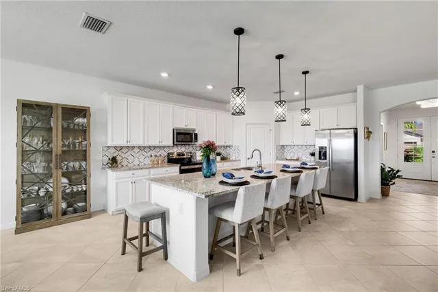 a large kitchen with kitchen island a dining table chairs and white cabinets