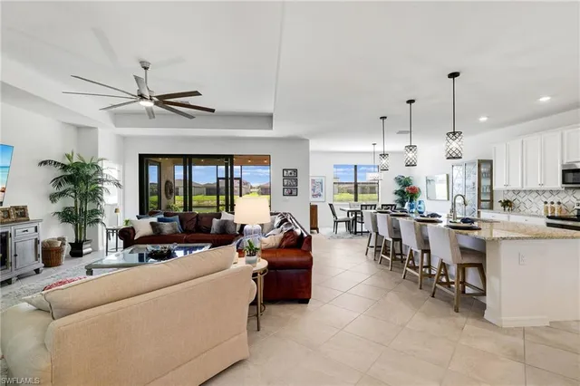 a living room with furniture kitchen view and a large window