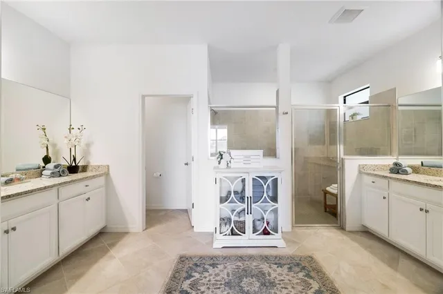 a spacious bathroom with a double vanity sink a mirror and a shower