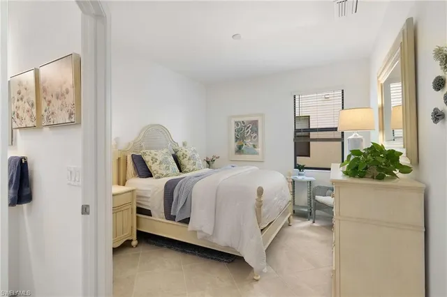 a bedroom with a bed and a potted plant on the dresser