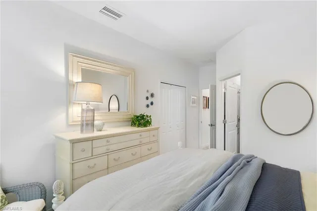 a bedroom with a bed a mirror and a potted plant