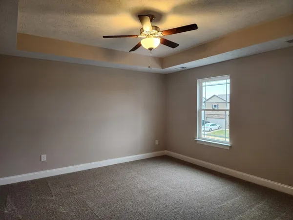 a view of an empty room with a ceiling fan and window