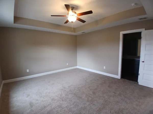 an empty room with wooden floor closet and windows