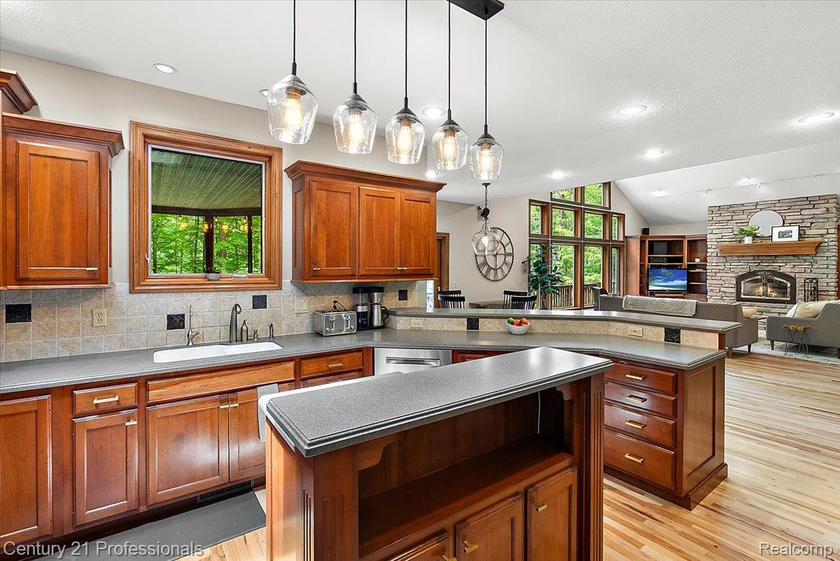 9867 Rainbow Ridge Drive Schoolcraft, MI 49087 - Photo 24 of 82 Open-concept kitchen featuring wood-finish cabinetry, solid surface countertops, and a multi-light pendant fixture