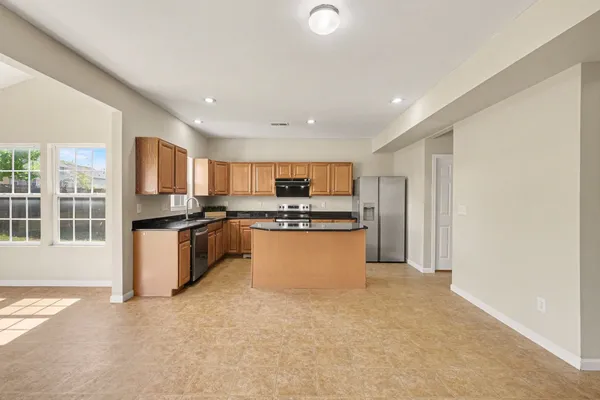 a large kitchen with granite countertop a large counter top stainless steel appliances and cabinets