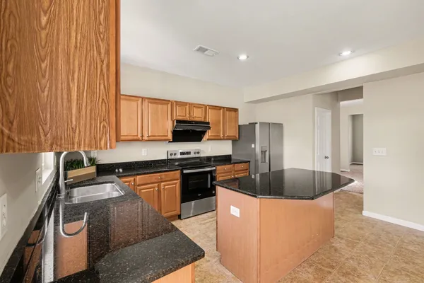 a kitchen with stainless steel appliances granite countertop a sink a stove and a refrigerator