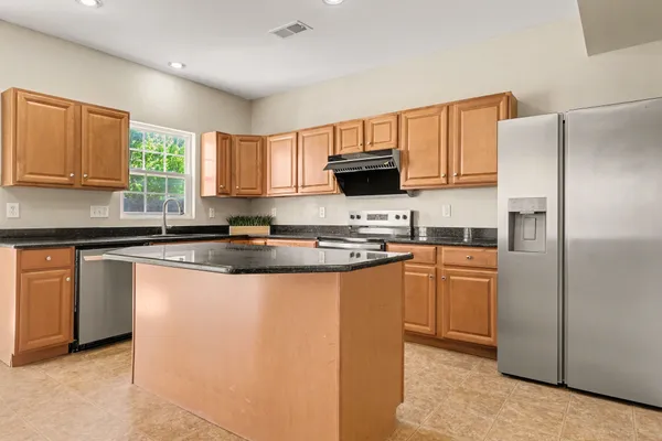 a kitchen with granite countertop a refrigerator sink and cabinets