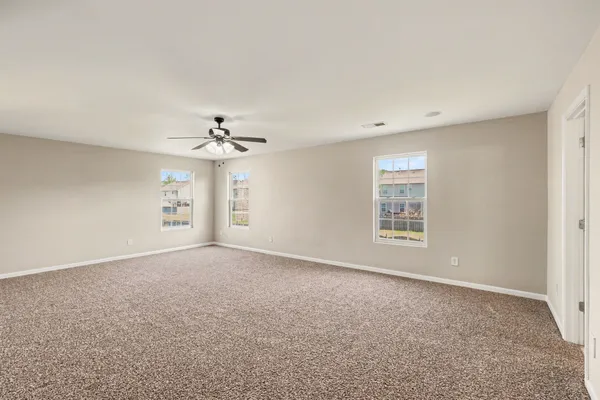 an empty room with windows and ceiling fan