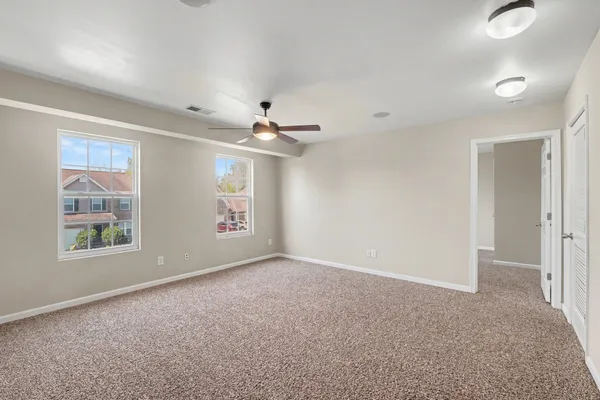 an empty room with windows and fan