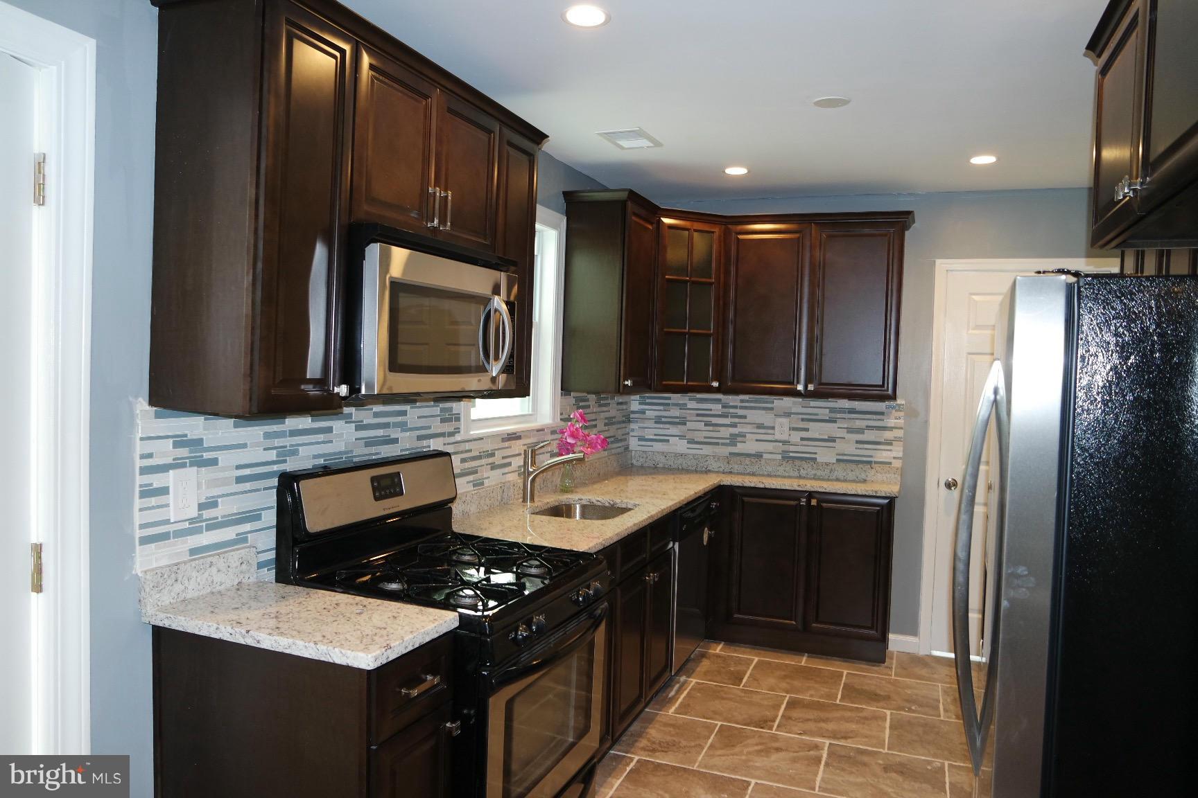 6716 Larkspur Road Morningside, MD 20746 - Photo 2 of 23 a kitchen with stainless steel appliances granite countertop wooden cabinets and a stove top oven
