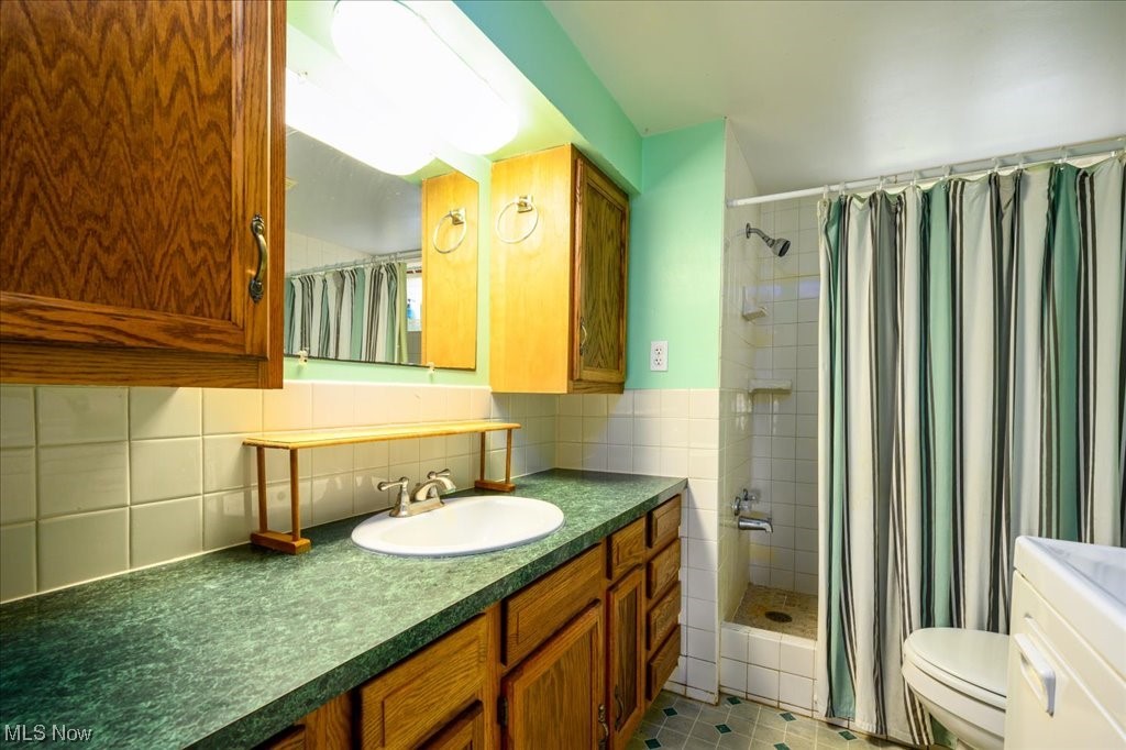 2641 Tower Road Jefferson, OH 44047 - Photo 20 of 35 Bathroom featuring large vanity, tasteful backsplash, curtained shower, toilet, and tile flooring