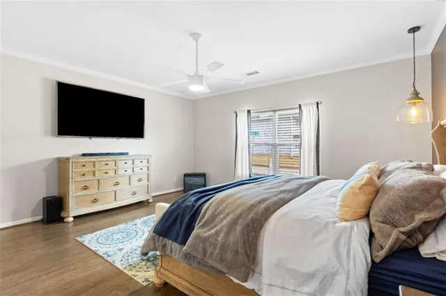 a spacious bedroom with a bed a flat screen tv and windows