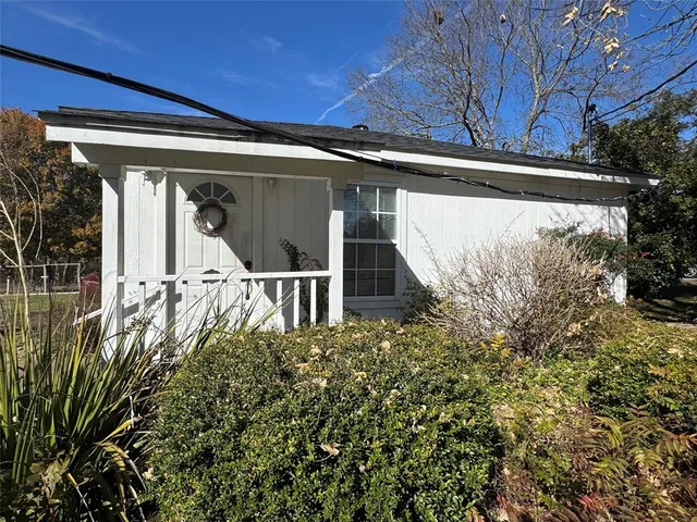 a view of a small house with a large window and potted plants