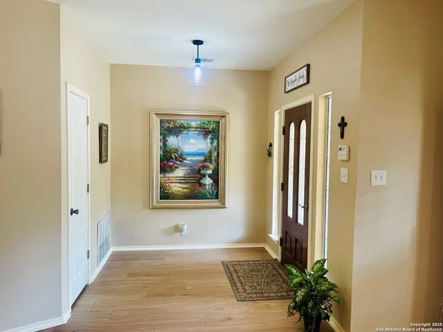 a view of a hallway with wooden floor and a bathroom