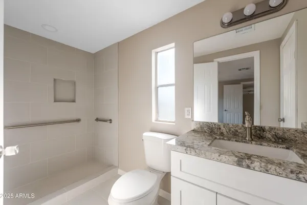 a bathroom with a granite countertop toilet sink and mirror