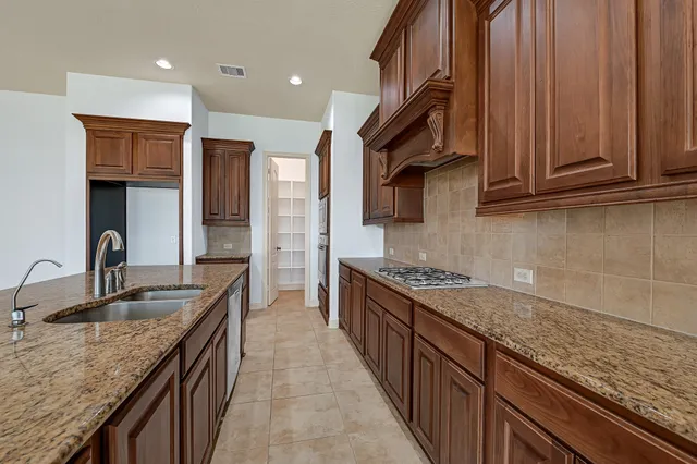 a kitchen with granite countertop a sink stove and cabinets