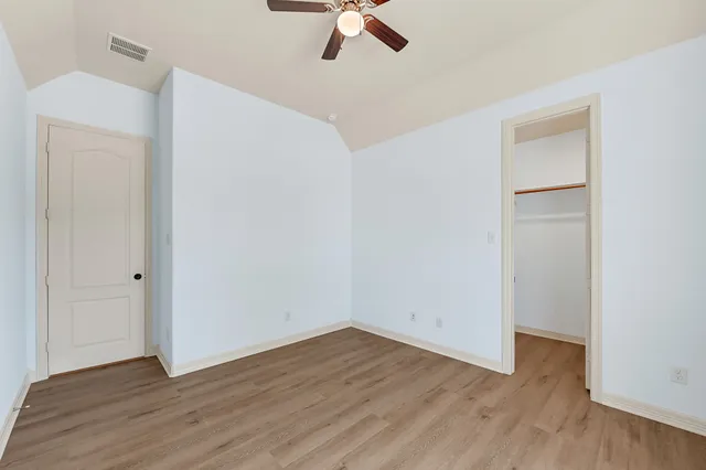 an empty room with wooden floor cabinet and a ceiling fan