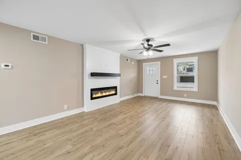 a view of an empty room with a window and wooden floor