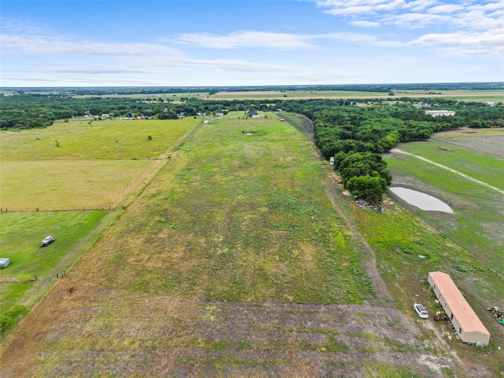 0 Ewing Road Ferris, TX 75125 - Photo 28 of 29 Expansive open land featuring a large pond, perimeter tree line, and a single-story outbuilding