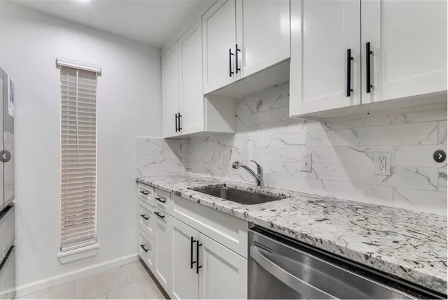 a kitchen with granite countertop white cabinets and a sink