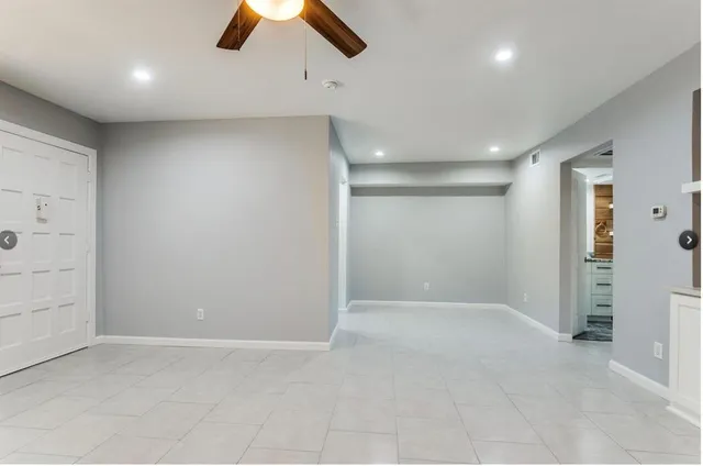 an empty room with ceiling fan and window