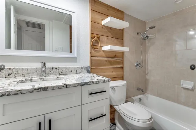 a bathroom with a granite countertop sink toilet and shower