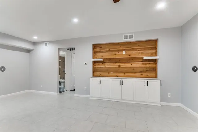a view of an empty room with cabinet and mirrors