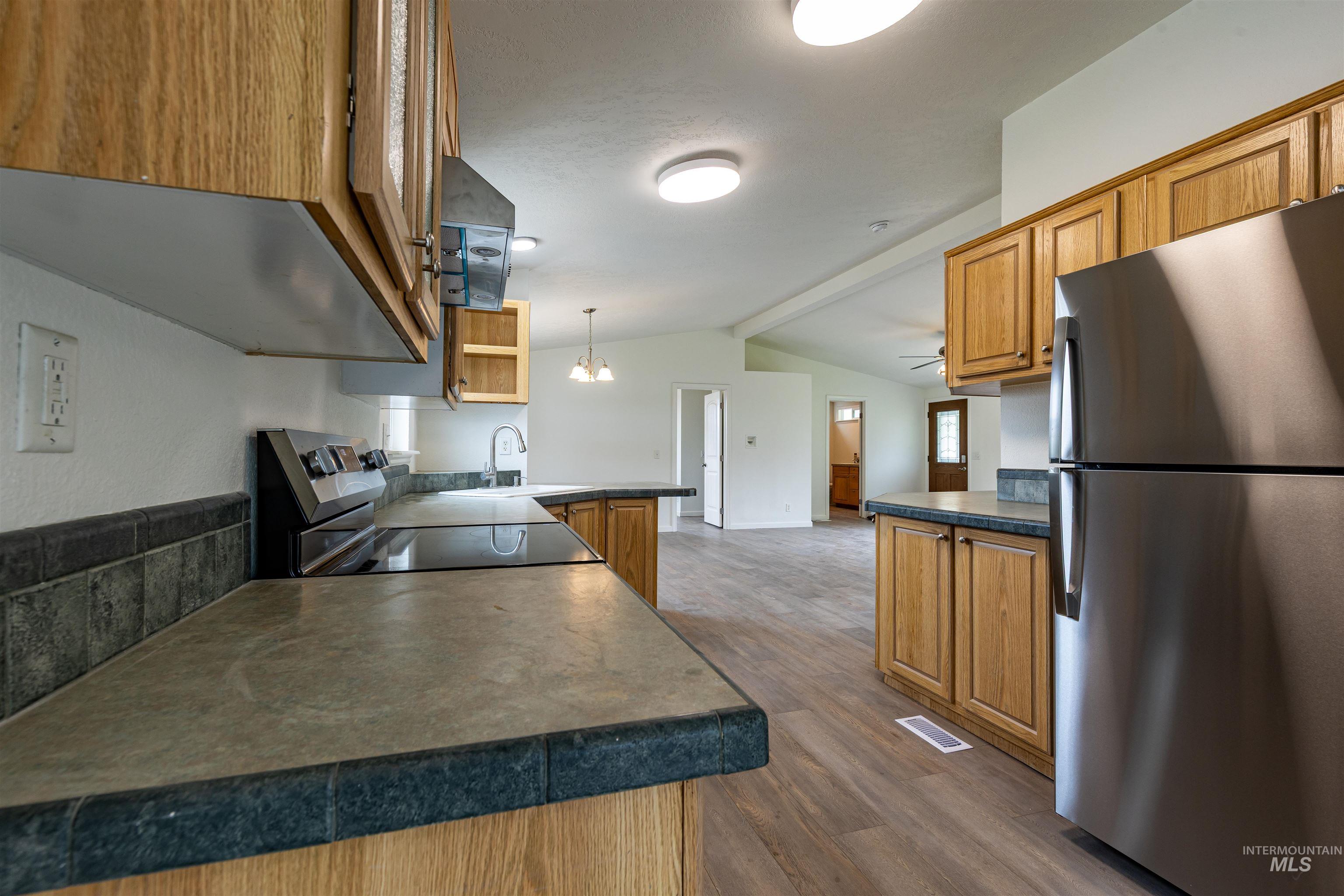 17028 Lower Pleasant Ridge Road Caldwell, ID 83607 - Photo 15 of 21 Kitchen featuring light wood cabinetry, dark countertops, tile backsplash, and stainless steel appliances