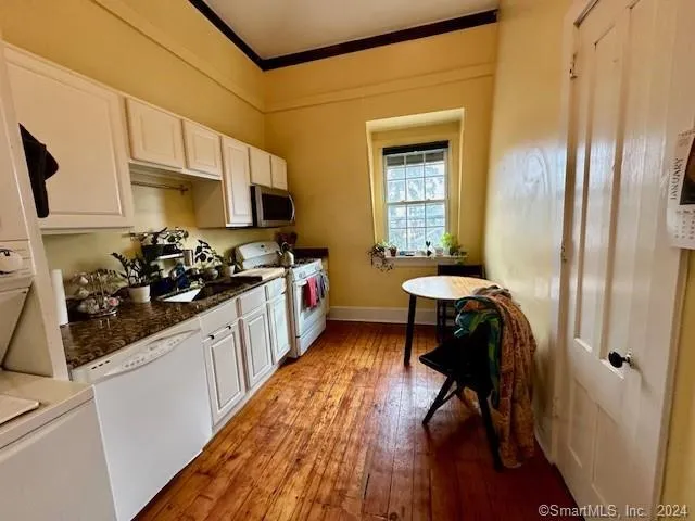 a kitchen with stainless steel appliances a stove a sink dishwasher and a refrigerator with wooden floor