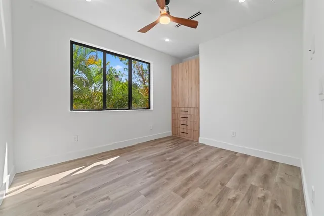a view of an empty room with a window and wooden floor
