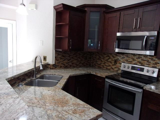 1564 Sunset Way Weston, FL 33327 - Photo 35 of 40 a kitchen with granite countertop a sink and a stove top oven with granite countertops