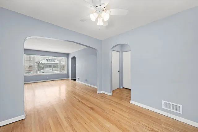 a view of an empty room with window and wooden floor