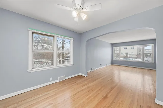 a view of an empty room with window and wooden floor