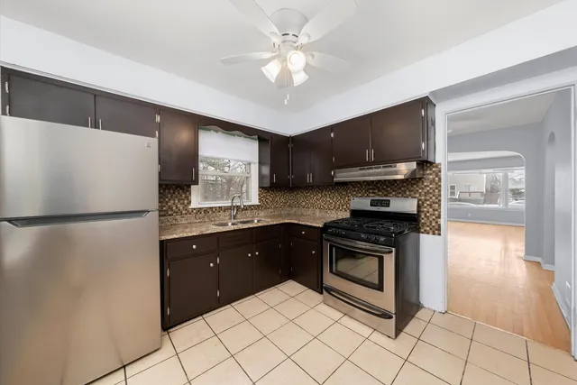 a kitchen with stainless steel appliances granite countertop a refrigerator a stove a sink and a microwave