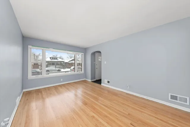 a view of an empty room with a window and wooden floor