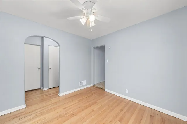 an empty room with wooden floor and a ceiling fan