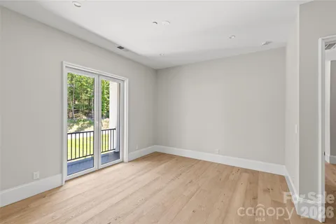 a view of an empty room with wooden floor and closet